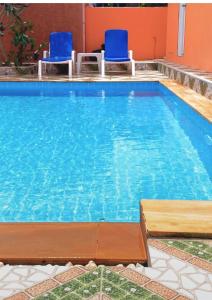 a large swimming pool with two blue chairs in it at Chalong pool villa in Ban Na Bon