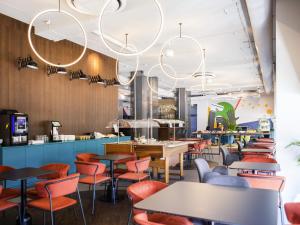 ein Restaurant mit bunten Stühlen und Tischen und einem Kronleuchter in der Unterkunft IBIS Styles Kaunas Centre in Kaunas