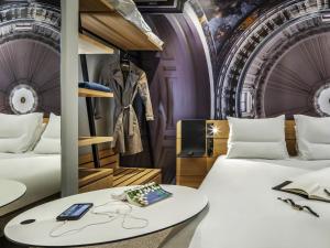 a room with two beds and a table with glasses at Novotel Paris 20 Belleville in Paris