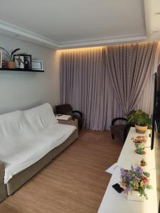 Una sala de estar con una cama y una mesa con flores. en Linda Casa centro de Bal Camboriú, en Balneário Camboriú