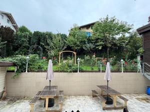 two picnic tables with umbrellas in front of a garden at Studio apartment - Park view - for 2 guests in Thun +5 photos