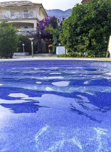 a swimming pool with blue water in front of a house at Apartments Iva in Orebić