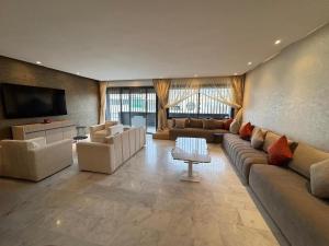 Il comprend un grand salon avec des canapés et une télévision à écran plat. dans l'établissement Comfortable 3 bedroom apartment ideally located, à Fès