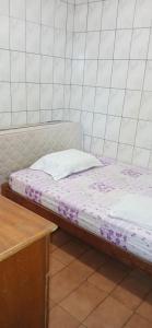 a bed in a room next to a wooden table at Cantinho aconchegante in Praia Grande
