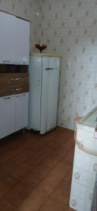 a kitchen with a white refrigerator in a room at Cantinho aconchegante in Praia Grande