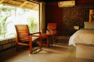 a bedroom with two chairs and a bed and a window at Misty Night Wayanad Pool Resort in Wayanad