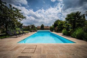 a large swimming pool with chairs and a cloudy sky at Maison Piscine & Tennis - Collection Idylliq in Muids