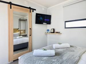 ミッドラントにあるBeds Inn Midrandのベッドが2つと壁にテレビがある寝室