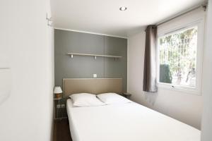 une chambre avec un lit blanc et une fenêtre dans l'établissement Camping International, à Calvi 65 autres photos