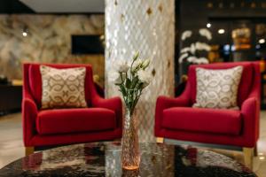 two red chairs and a vase with flowers on a table at Favor Park Hotel in Kyiv