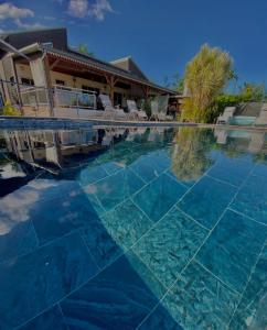 a swimming pool with blue water in front of a house at Villa Le Coin de Paradis in Saint-Leu