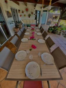 a long wooden table with plates and flowers on it at Villa Le Coin de Paradis in Saint-Leu