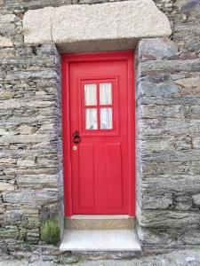 a red door in a stone wall at Refúgio no Douro in Nogueira