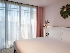 a bedroom with a white bed and a large window at Mama Shelter Lisboa in Lisbon