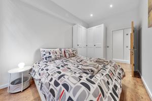a bedroom with a bed with a black and white comforter at Shortlet Express, Stunning 3 bedroom Barking Apartment, by Train Station in Barking +12 photos