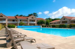una piscina con sedie a sdraio di fronte a una casa di Résidence Goélia Le Cordouan a Soulac-sur-Mer