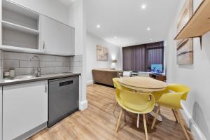 a kitchen with a wooden table and yellow chairs at Shortlet Express, Stunning 3 bedroom Barking Apartment, by Train Station in Barking