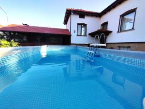 a swimming pool with a chair in front of a house at Къща за гости При Комина - Guest House By the Chimney in Dryanovo