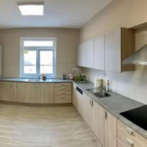 a large kitchen with white cabinets and a window at Malom Munkásszálló in Karcag