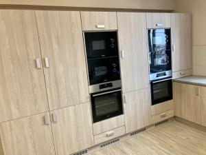 a kitchen with wooden cabinets with two microwaves at Malom Munkásszálló in Karcag