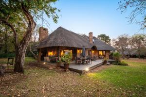 Kruger Park Lodge Unit No 304 في هازيفيو: منزل به سقف من القش مع فناء