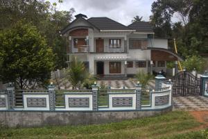 a house with a fence in front of it at Aashiyana Idukki in Kūmudi