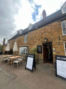a restaurant with tables and umbrellas in front of a building at The George Inn in Lower Brailes +23 photos