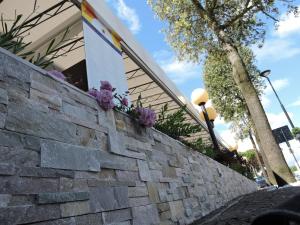 a stone retaining wall with purple flowers on it at Hotel Berna in Eraclea Mare