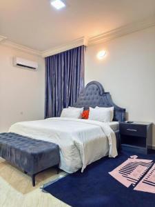 MobushipeにあるKB's Residence - Three Bedroom Near Wuse IIのベッドルーム1室(大型ベッド1台、青いタフトのヘッドボード付)