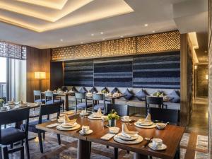 a restaurant with wooden tables and chairs and a large wall at Pullman Dali in Dali