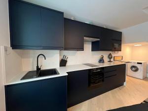 a kitchen with black cabinets and a sink at Modern Studio Living, 300m from Totteridge & Whetstone Station in Whetstone