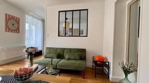 a living room with a green couch in a room at La Bulle Millésimée - à deux pas de la Gare et de l'Avenue de Champagne in Épernay +34 photos