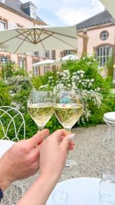 two people holding up glasses of white wine at La Bulle Millésimée - à deux pas de la Gare et de l'Avenue de Champagne in Épernay