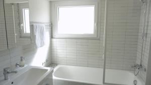 Un baño blanco con bañera y lavabo. en Alpine Nest Crans-Montana, en Lens 23 fotos más