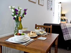 a table with two plates of food and a vase of flowers at Devon Villa Garden Apartment in Torquay +8 photos