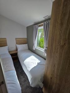 Great ClactonにあるNew - 3 bedroom Caravan, 140 Pasture Laneの窓のある部屋にベッドが2つある