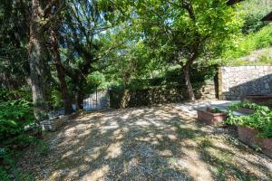 a backyard with trees and a stone wall and a bench at Villa Alexandra by MMega in Riomagno