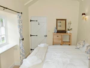 ein Schlafzimmer mit einem weißen Bett und einem Spiegel in der Unterkunft Game Larder Cottage in Saint Mabyn + 2 Fotos