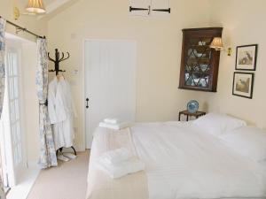 ein Schlafzimmer mit einem großen weißen Bett und einem Fenster in der Unterkunft Game Larder Cottage in Saint Mabyn