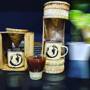 a glass of tea sitting next to two tea cups at Raya Homestay Rammang Rammang in Kasijala +70 photos