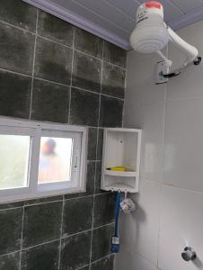 a bathroom with a window and a tile wall at Apêzinho de Luxo Morros in Morros
