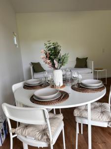 a white dining room table with white plates and chairs at Lodges La Chouette Nuit in Ernemont-Boutavent