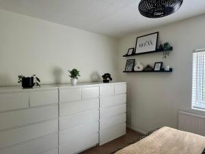 une pièce avec des armoires blanches et des plantes sur le mur dans l'établissement Modern 2-Bed Home with great location in Luton, à Luton
