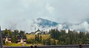 a small town with a church and a mountain at Apartamenty pod Tatrami in Zakopane +5 photos