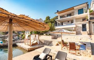 un patio avec des chaises et des parasols en face d'un bâtiment dans l'établissement Waterfront villa Marija by Villas Guide, à Potirna