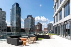 a patio with couches and tables and a city skyline at Blueground Clinton Hill rooftop pool nr Prospect Park NYC-1961 in Brooklyn