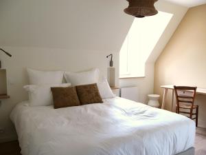 a bedroom with a large white bed with a window at Le bois salé - Maison de charme dans le parc du Domaine du Cloitre in Pléneuf-Val-André