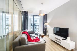 a living room with a couch and a television at Browar Gdański Superior Apartments by Noclegi Renters in Zaspa +11 photos