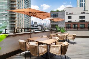 ロング・アイランド・シティにあるEVEN Hotel Long Island City - New York by IHGの屋上にテーブルと椅子、パラソル付きのパティオ