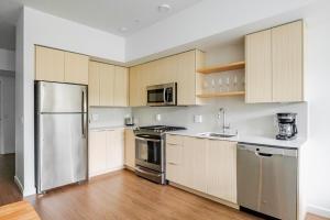 a kitchen with wooden cabinets and stainless steel appliances at Blueground Downtown rooftop nr Marymoor Park SEA-890 in Redmond +22 photos